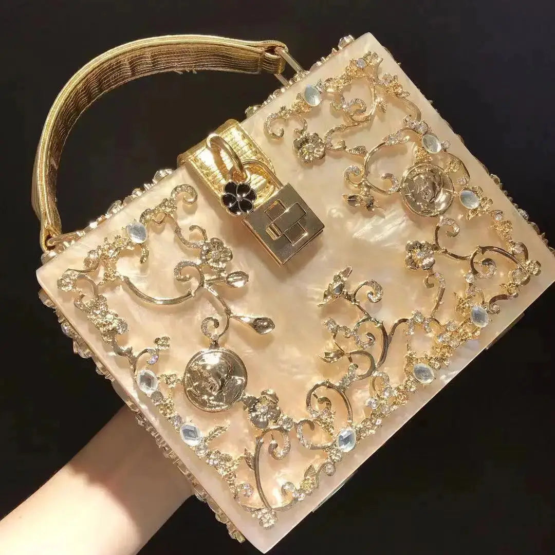 Evening bag with crystal embellishments and gold-tone floral filigree on a champagne clutch