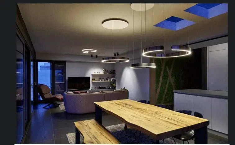 Ring ceiling chandelier with LED rings in black metal over a wooden dining table in a modern living area