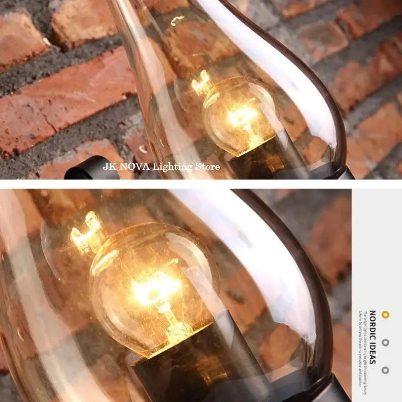Wall lamp in wrought iron with glass shade; industrial loft style, warm amber glow