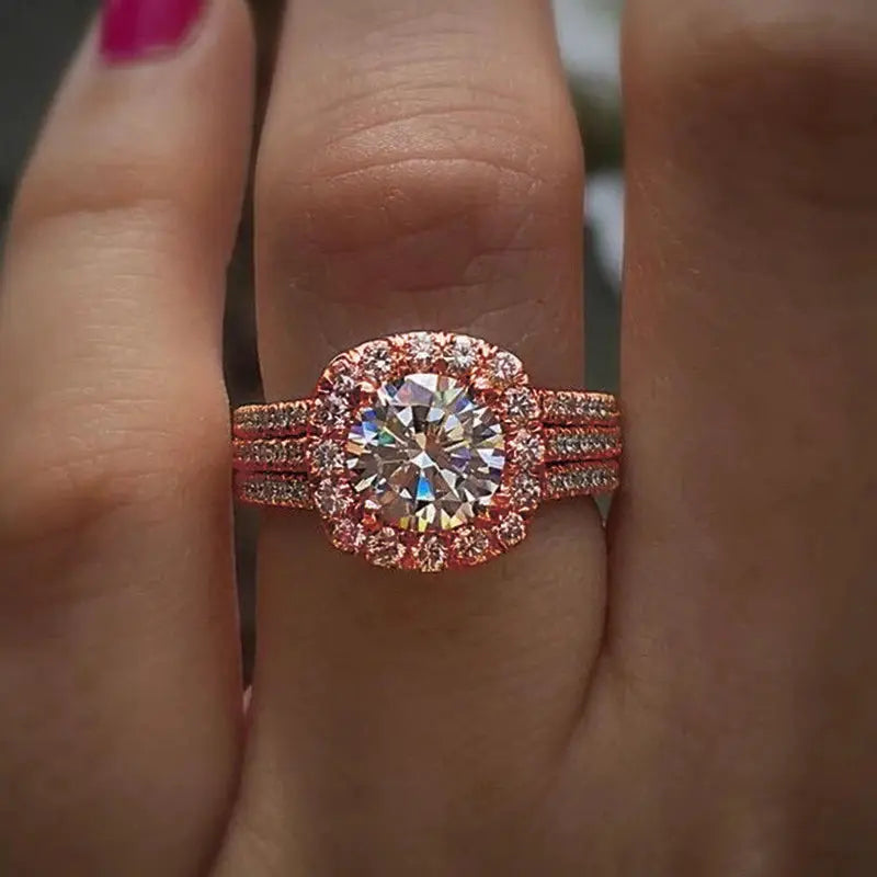 Rose gold brass engagement ring with a large center cubic zirconia and pave halo on a triple-band shank