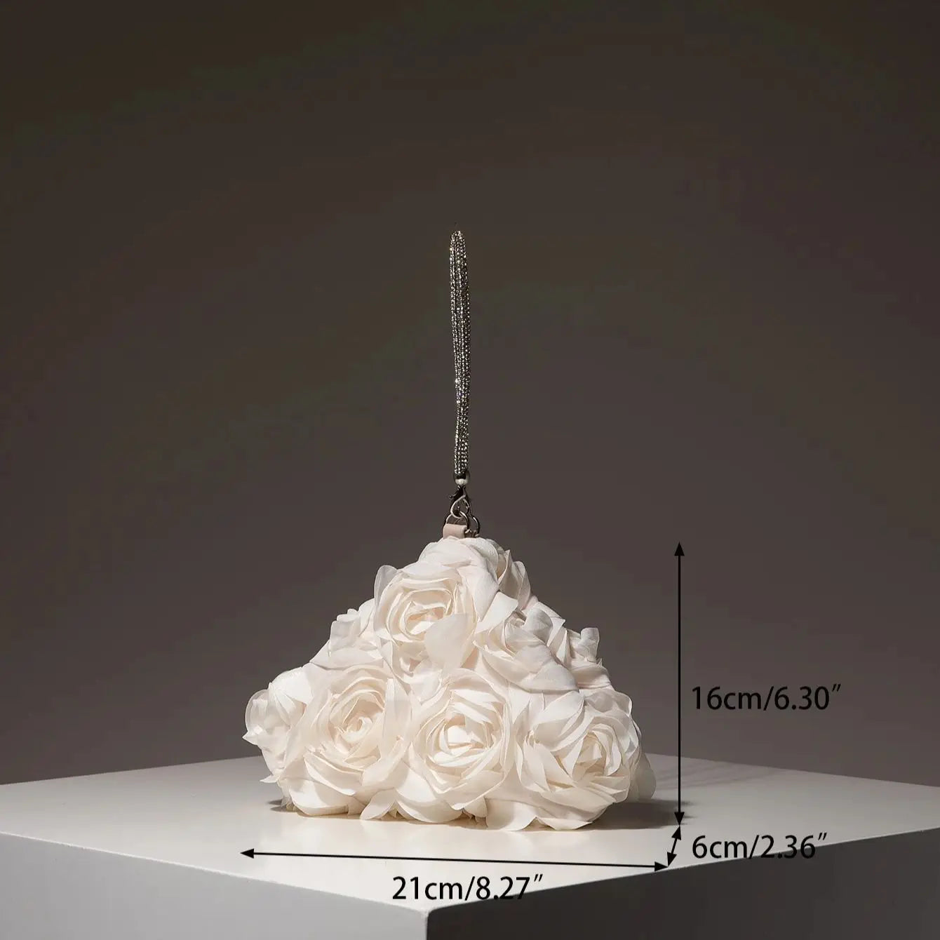 Mini bridal purse with a beaded silver strap atop a white rose bouquet; dimensions 21x6x16 cm.