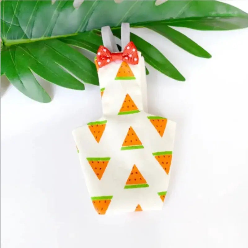 Parrot diaper with bowtie for small birds; white fabric with orange triangle fruit print, green accents, red bow.