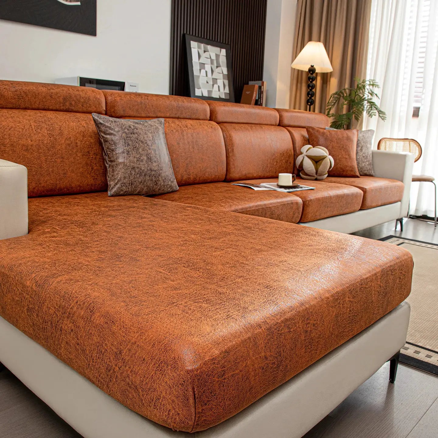Stretch sofa cover by Simples Market in burnt-orange fabric on a cream sectional, protects living room furniture.