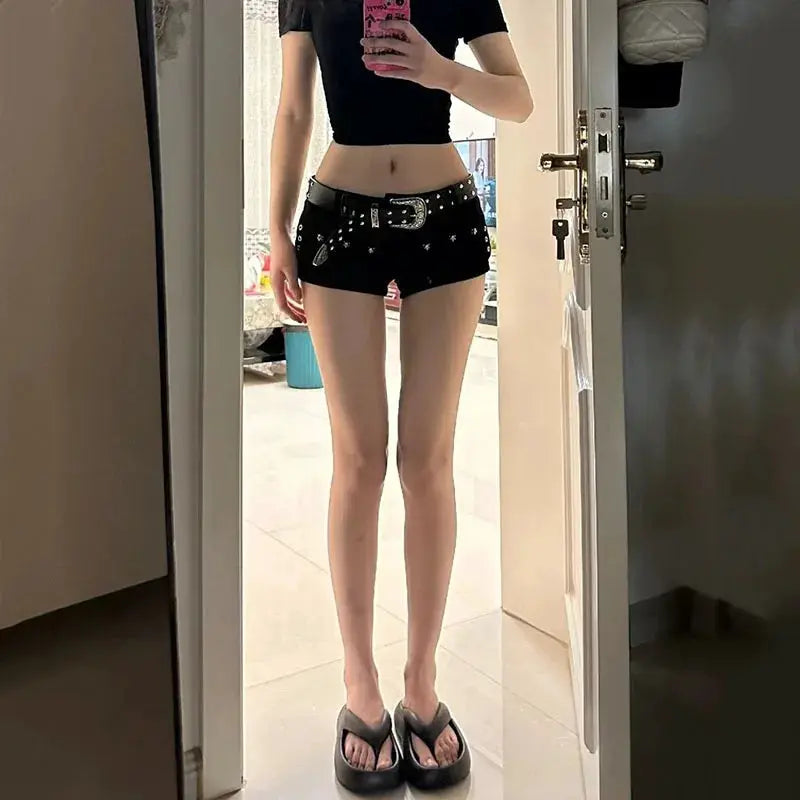 Black denim shorts with a studded belt, low-waist Y2K punk style