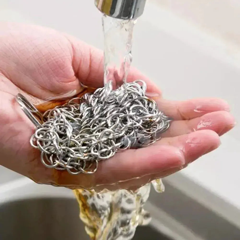Stainless steel chain mail scrubber for cast iron cookware, held under running water
