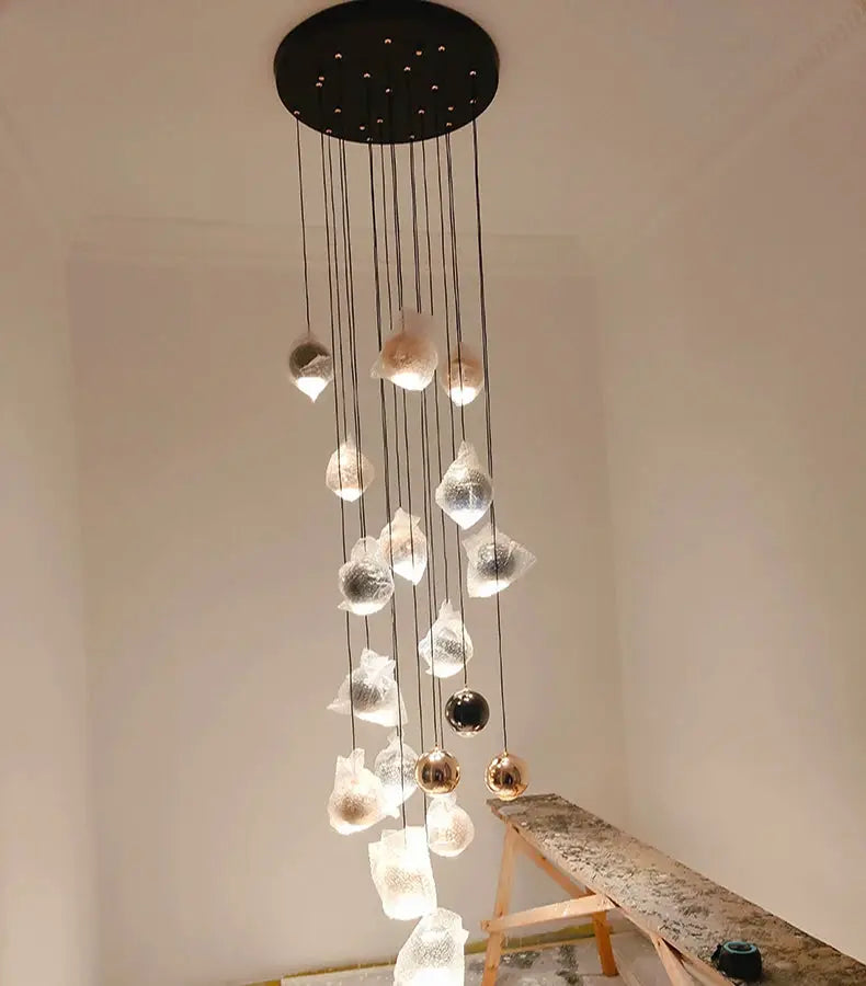Modern pendant light with multiple glass droplet pendants on a black canopy, LED illuminated.