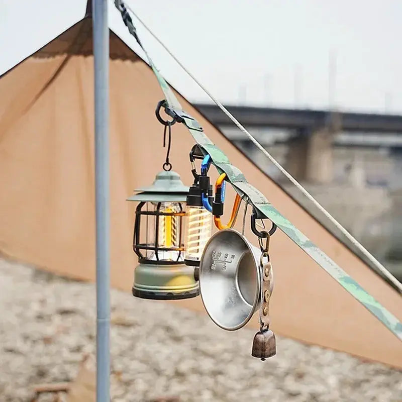 Outdoor crossbody strap Simples Market with adjustable length; green strap; camping gear hanging two lanterns and metal cup