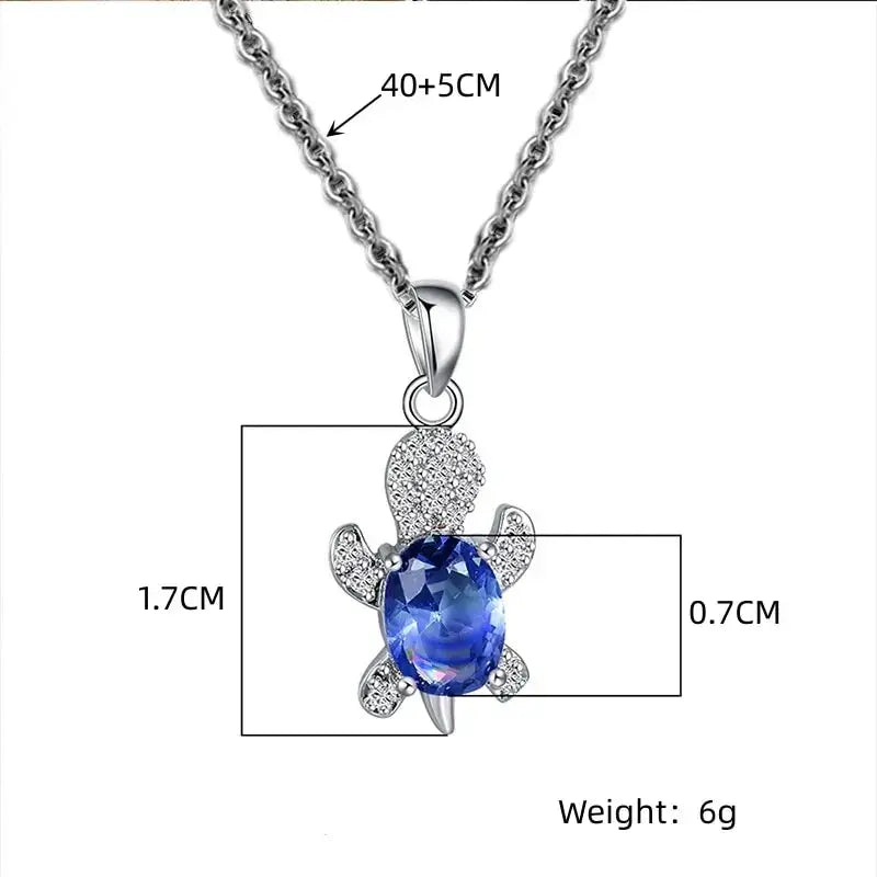 Turtle pendant necklace in silver-plated metal with blue gemstone and clear crystal accents; adjustable 40+5 cm.