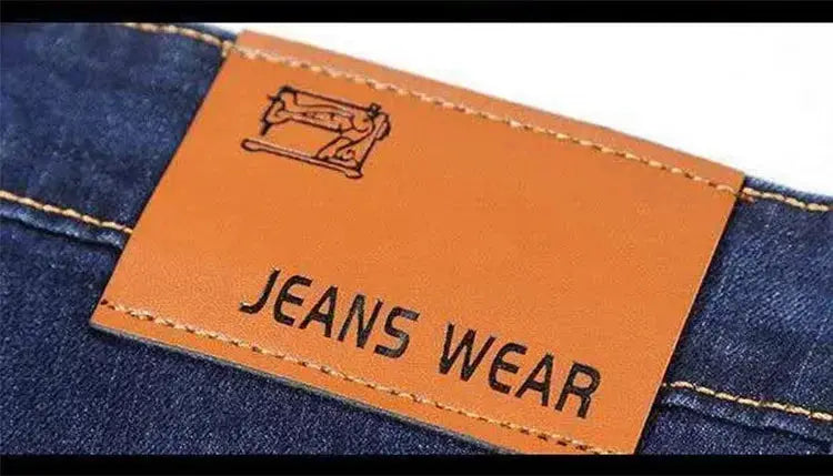 Jeans in blue denim with tan leather patch reading JEANS WEAR