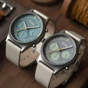 Two CILOA round gray-dial watches with silver cases and light gray straps.