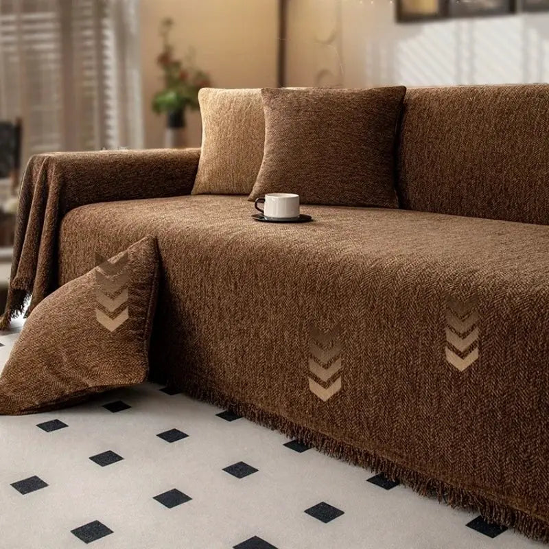 Brown chenille sofa throw with tassel edge on a brown living room sofa.