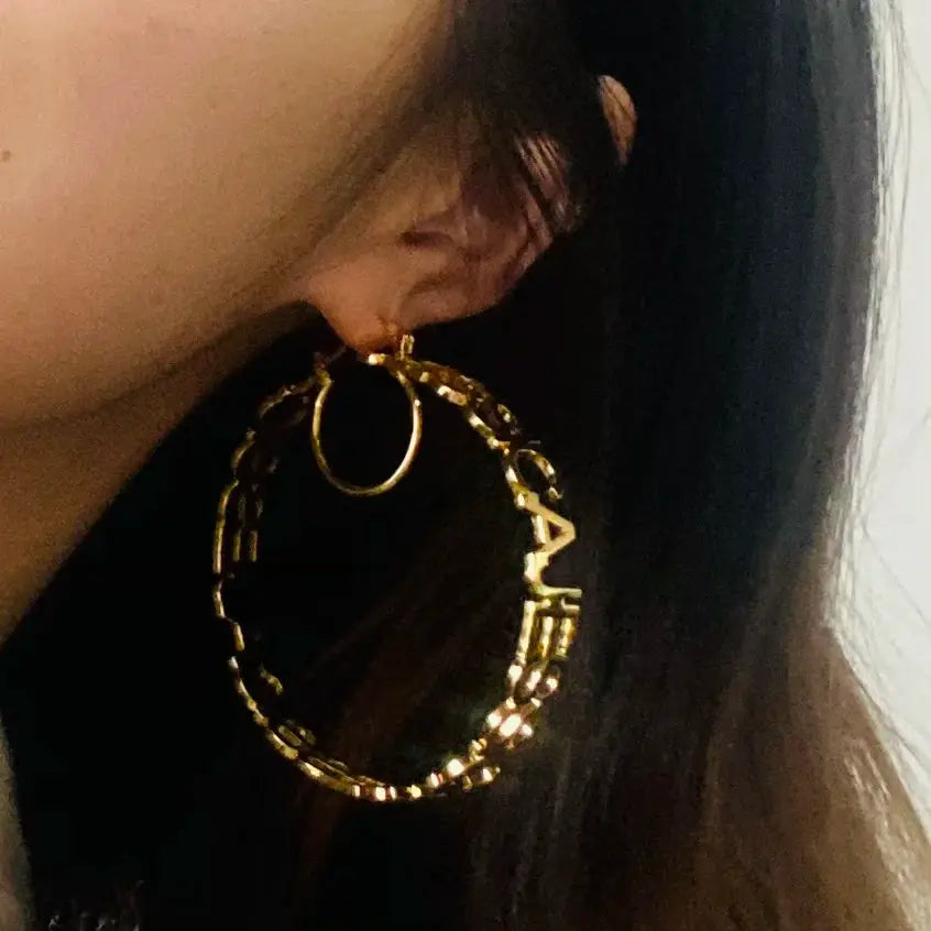 Gold-tone large hoop earrings with chain-link texture worn on the ear