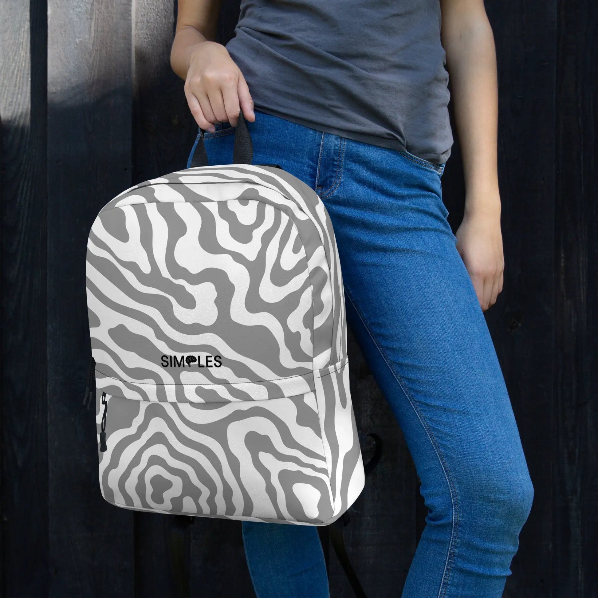 Backpack by Simples Market with gray zebra print pattern held by a person in blue jeans.