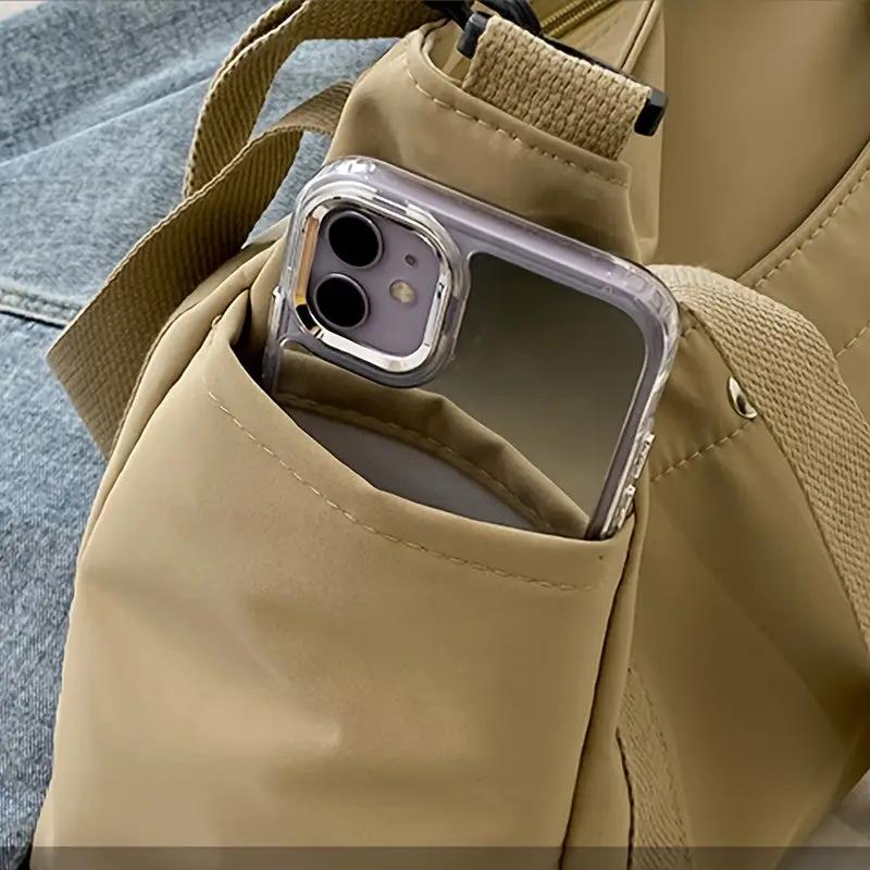 Large Capacity nylon crossbody bag in tan with removable strap and front pocket holding a smartphone