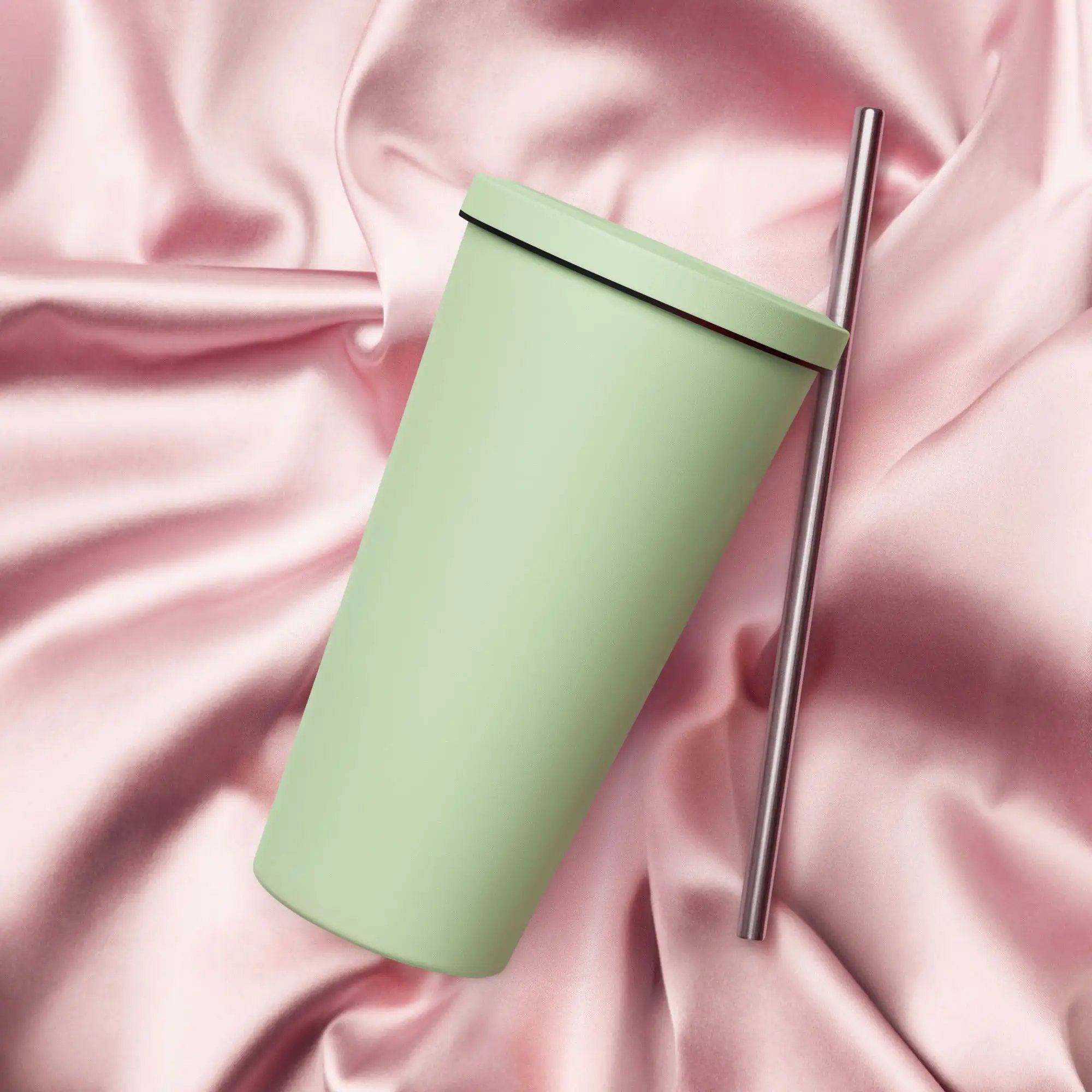 Insulated tumbler with lid and stainless steel straw, mint green, pink satin backdrop.