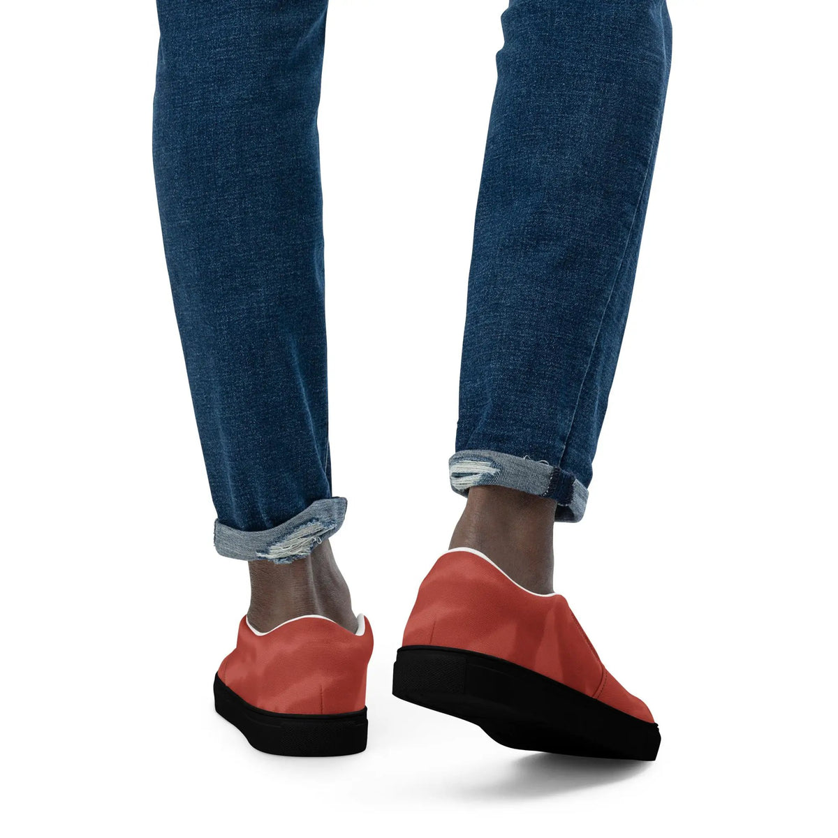 Men's slip-on canvas shoes in red; paired with rolled denim jeans