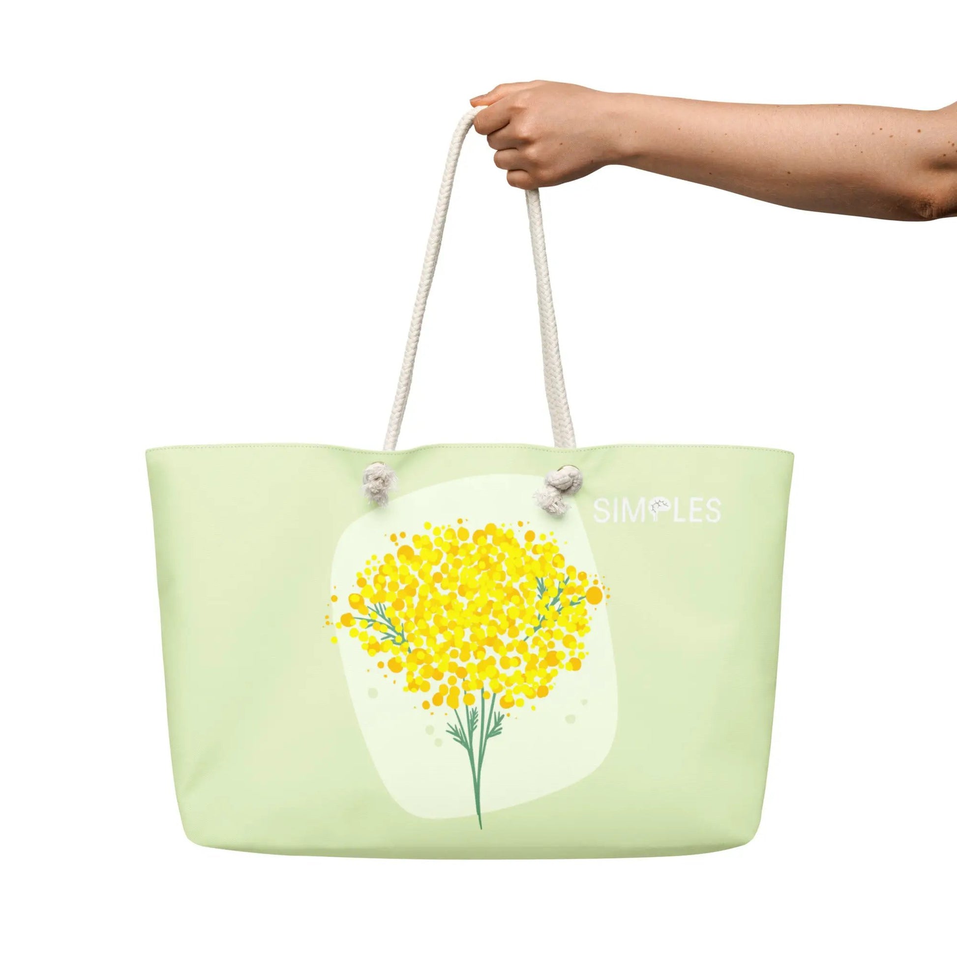 Oversized weekender bag by Simples Market in mint green with white rope handles and yellow floral print.