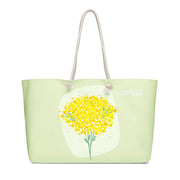 Oversized weekender bag in pale green with rope handles and a yellow floral print by Simples Market.