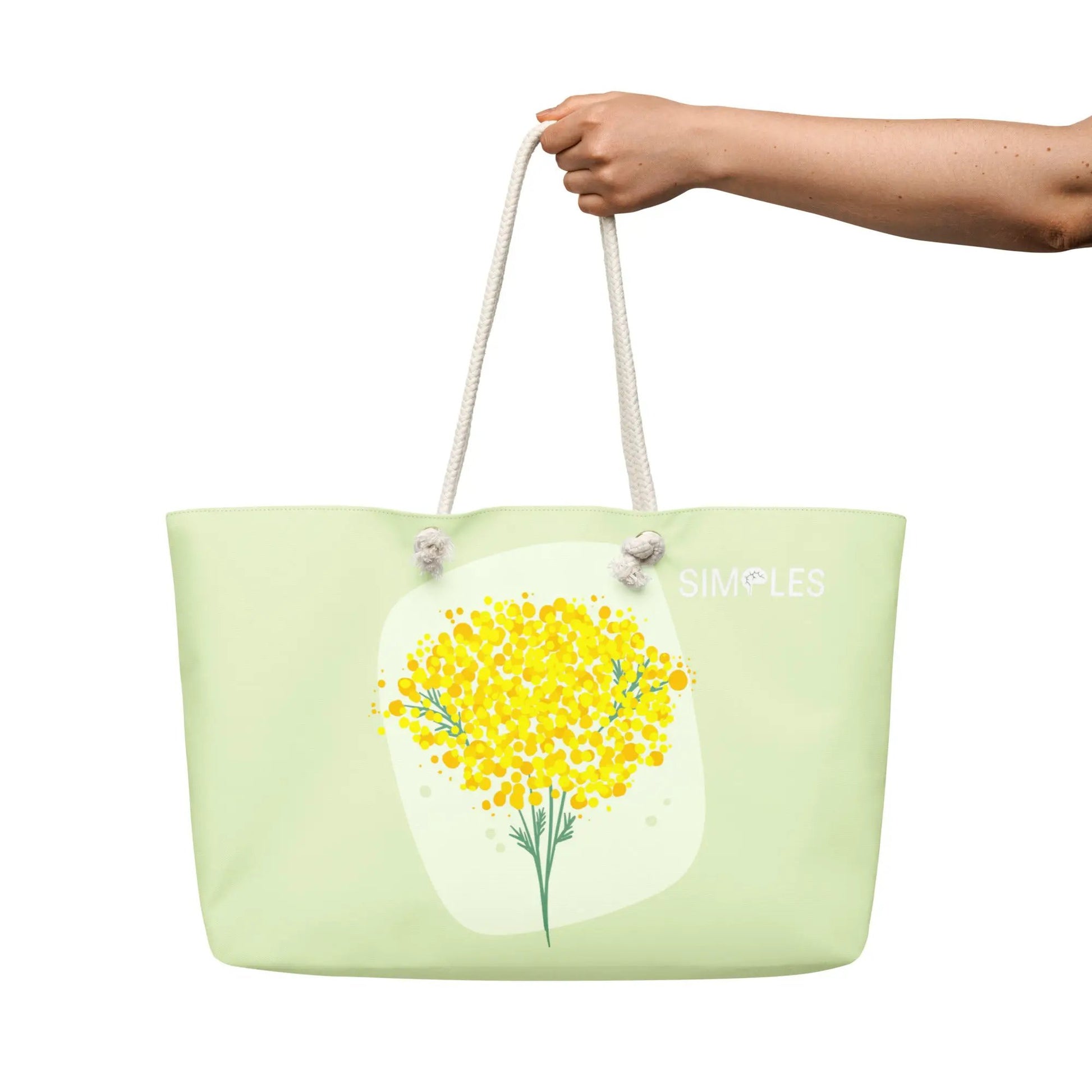 Oversized weekender bag by Simples Market; pale green with white rope handles and a yellow floral print.